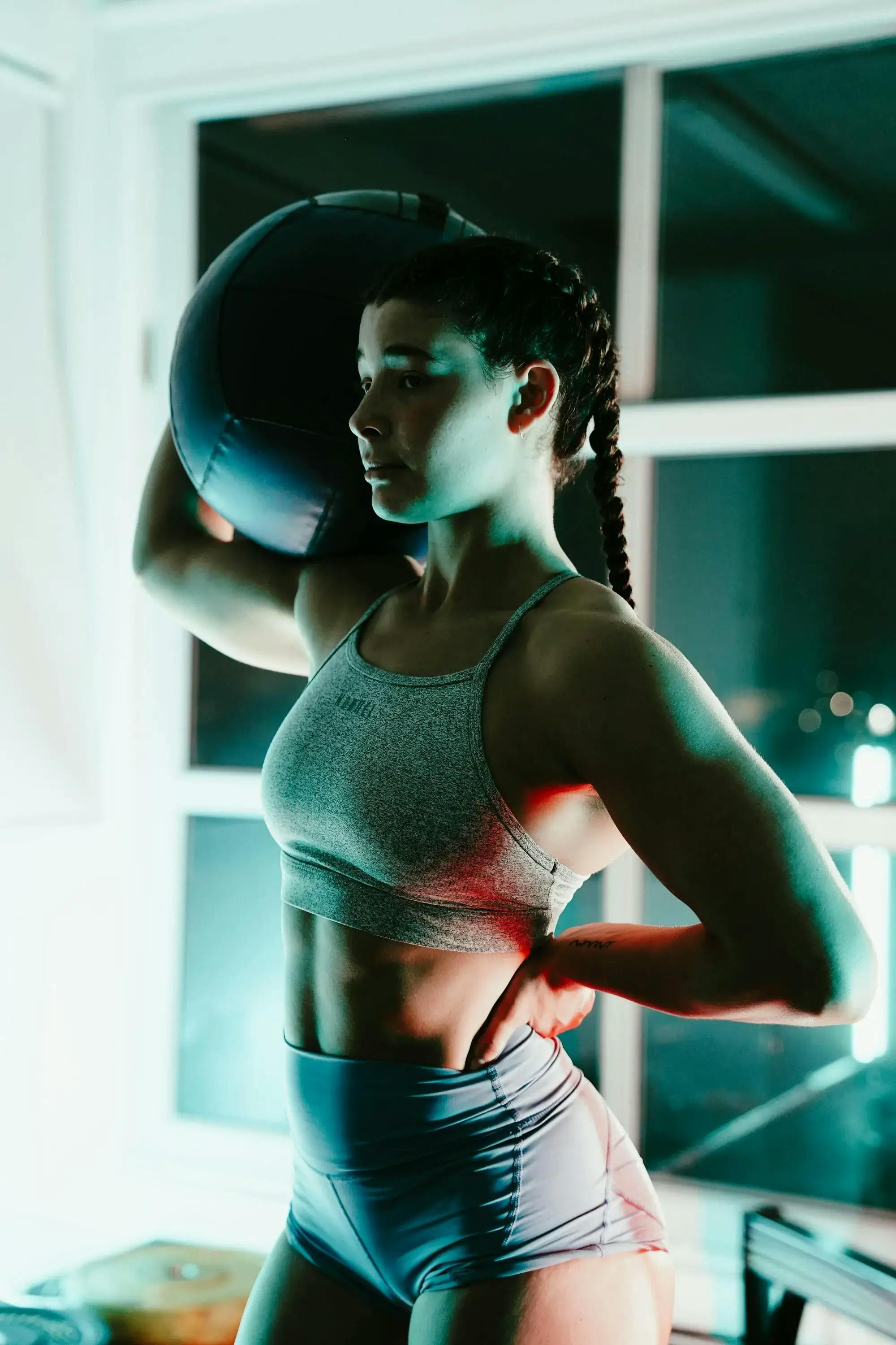 woman holding a fitness ball on her shoulder